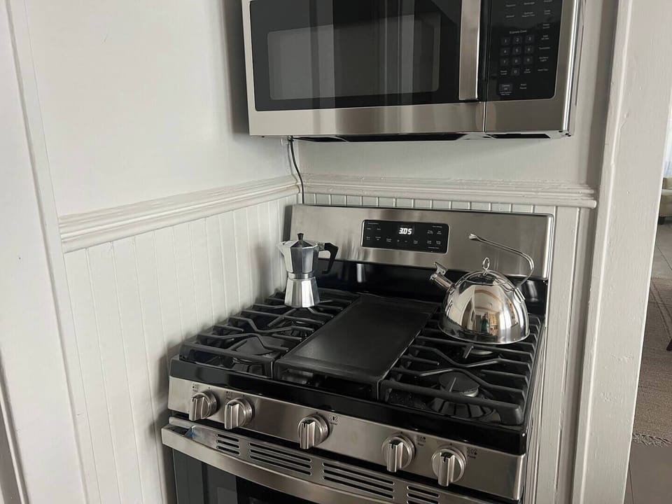 Indulge in culinary creativity in our sunlit kitchen oasis, featuring a charming butcher block countertop and airy floating shelving. Enjoy natural light as you prepare meals, surrounded by a modern, open-concept design that invites inspiration.