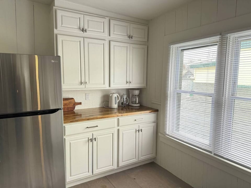 Indulge in culinary creativity in our sunlit kitchen oasis, featuring a charming butcher block countertop and airy floating shelving. Enjoy natural light as you prepare meals, surrounded by a modern, open-concept design that invites inspiration.