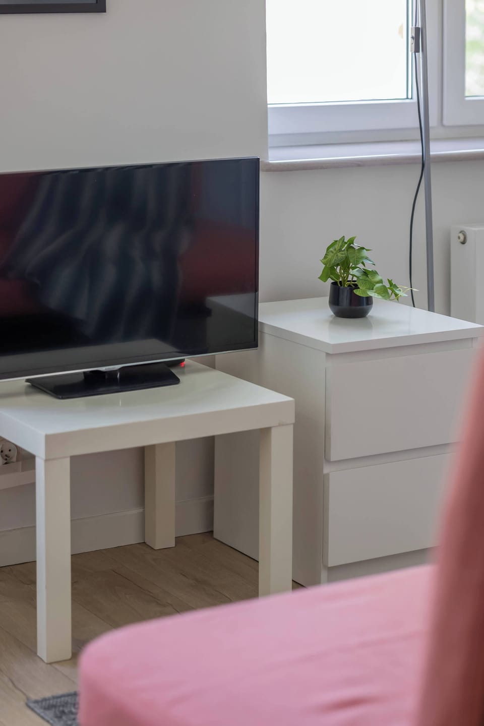 A close-up of the TV nook features a small flat-screen television on a white cabinet and two dining chairs.