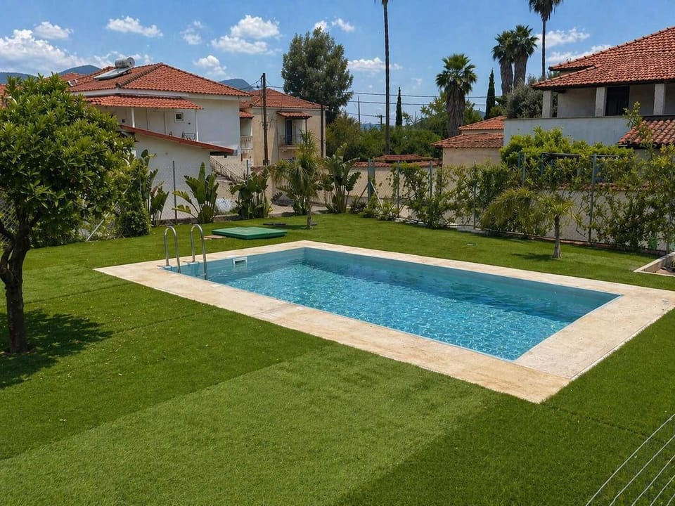 A closer view of the pool and garden highlights the open layout and easy access, creating a comfortable setting for cooling off, sunbathing, or gathering outside at your own pace.