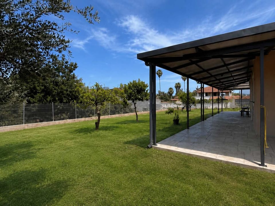 A shaded outdoor area with a pergola structure, offering a quiet spot to sit outside surrounded by dry earth and olive trees, ideal for slower moments during the day.