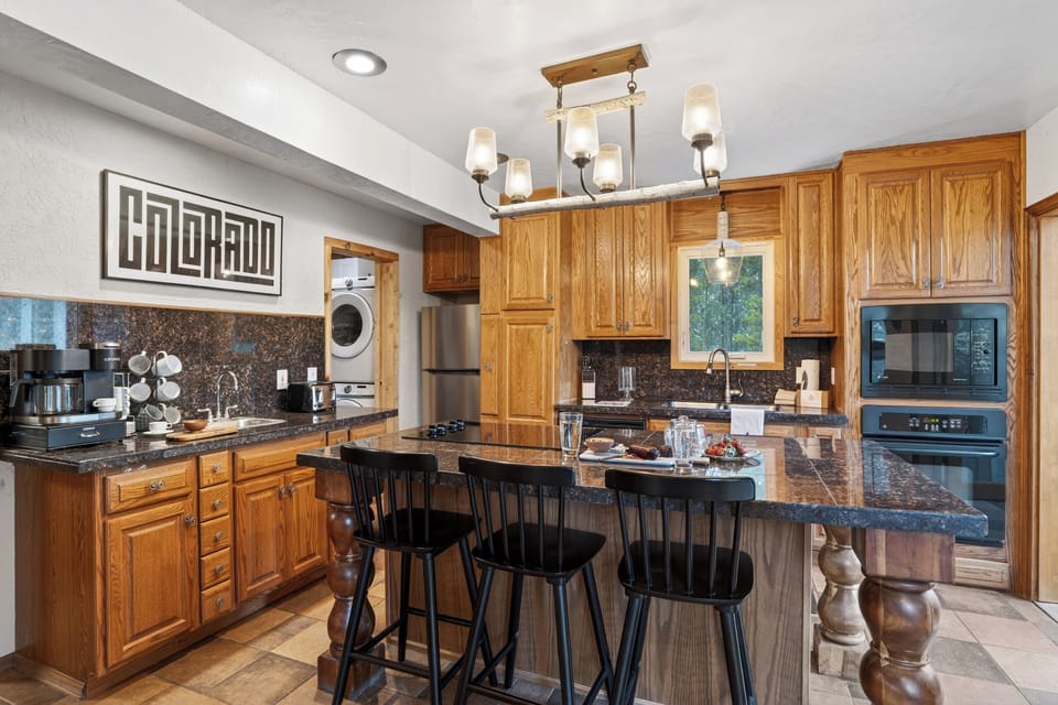 Spacious kitchen with rich wood cabinetry, granite counters, and island seating—perfect for gathering and entertaining.