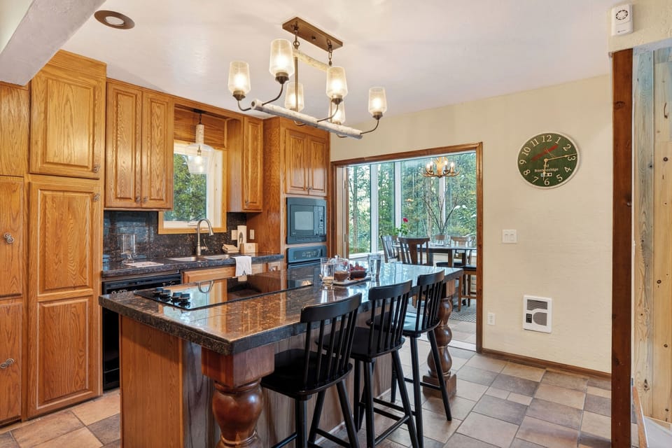 Spacious kitchen with rich wood cabinetry, granite counters, and island seating—perfect for gathering and entertaining.