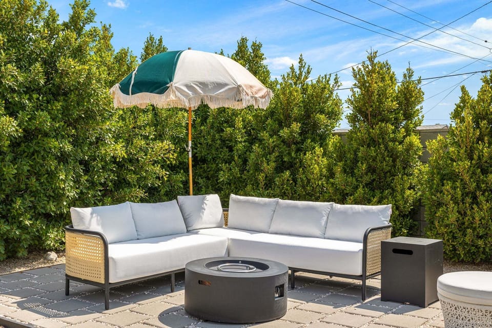 Outdoor lounge with fire pit, sectional seating & shaded umbrella