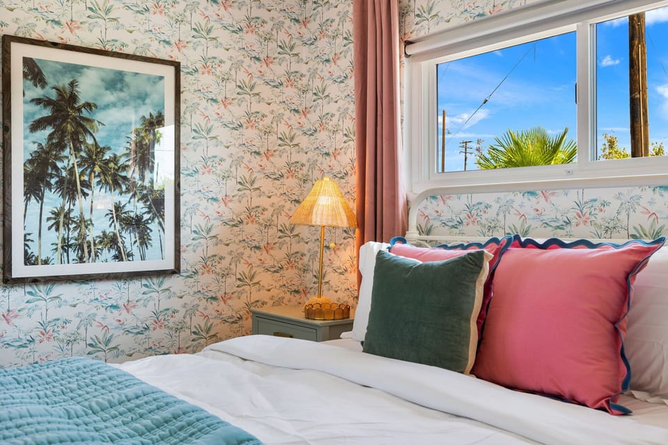 Light-filled bedroom with palm art, soft tones & cozy bedding