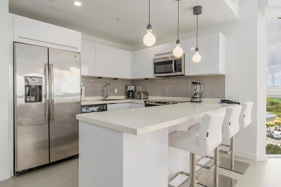 Your sleek modern kitchen awaits with premium stainless appliances, elegant pendant lighting, and a breakfast bar perfect for morning coffee.