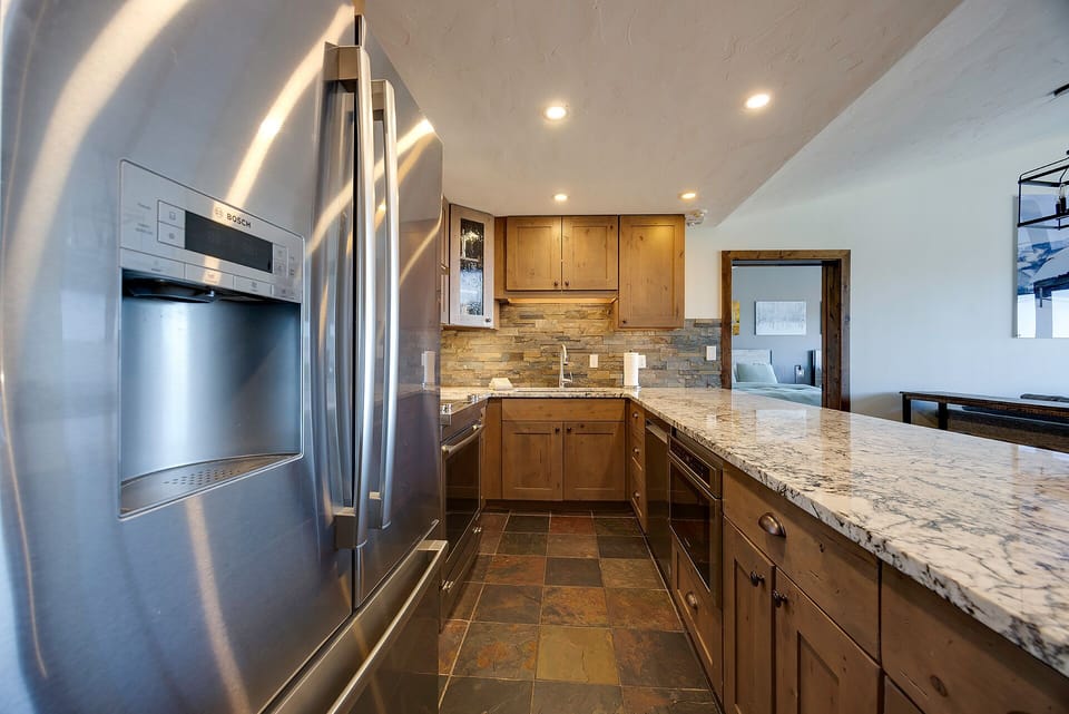 Step into your fully equipped gourmet kitchen with granite countertops, stainless steel appliances, and warm wood cabinetry perfect for home-cooked meals.
