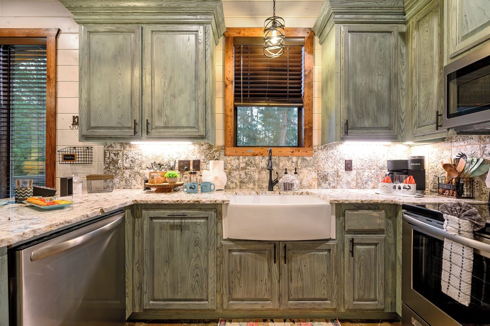You'll love cooking in this beautifully appointed kitchen with its rustic sage cabinetry, granite countertops, and charming farmhouse sink.