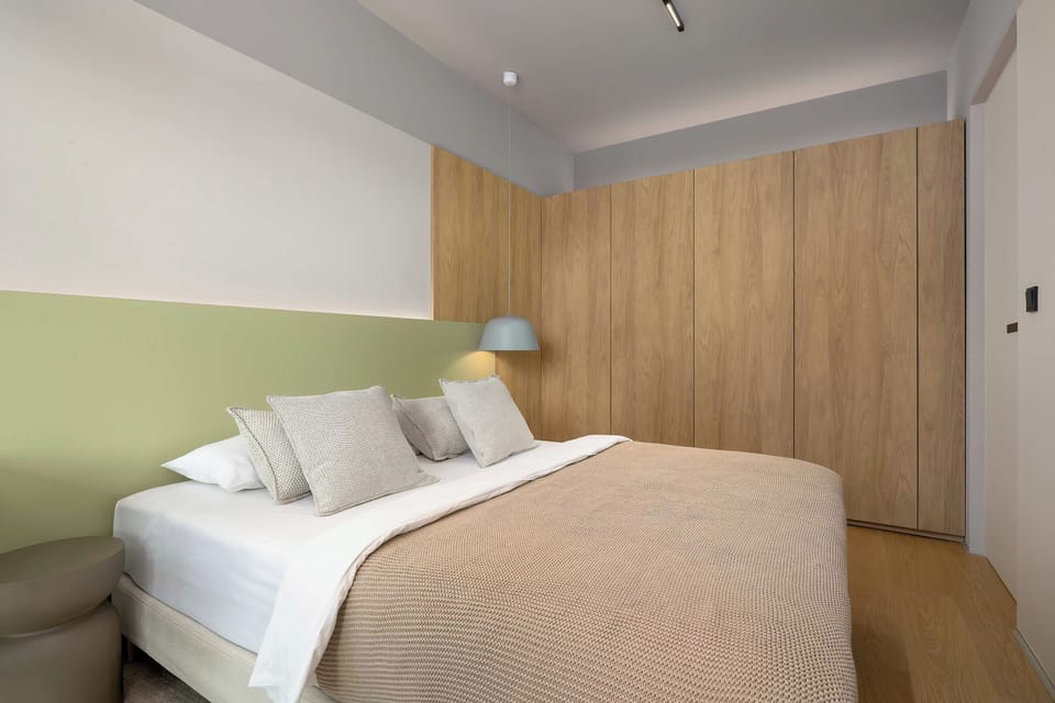 A modern bedroom with a double bed, wooden wall panels, and soft bedside lighting.