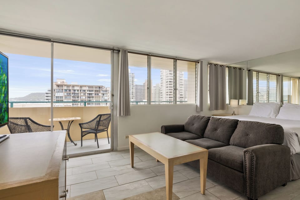 Unwind in your bright living space with panoramic city and ocean views through floor-to-ceiling windows and private balcony access.