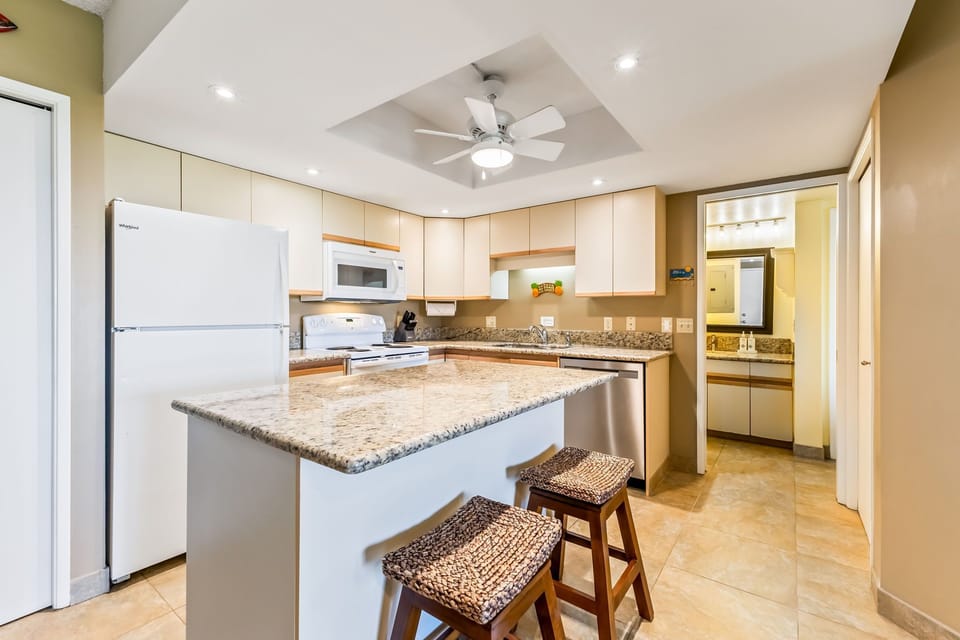 This fully equipped kitchen features granite countertops, modern appliances, and a center island perfect for preparing meals and gathering with loved ones during your stay.