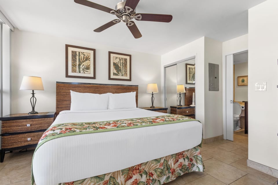 Sink into crisp white linens and tropical comfort in your elegant bedroom, where ceiling fan breezes and warm lighting create your perfect island retreat.