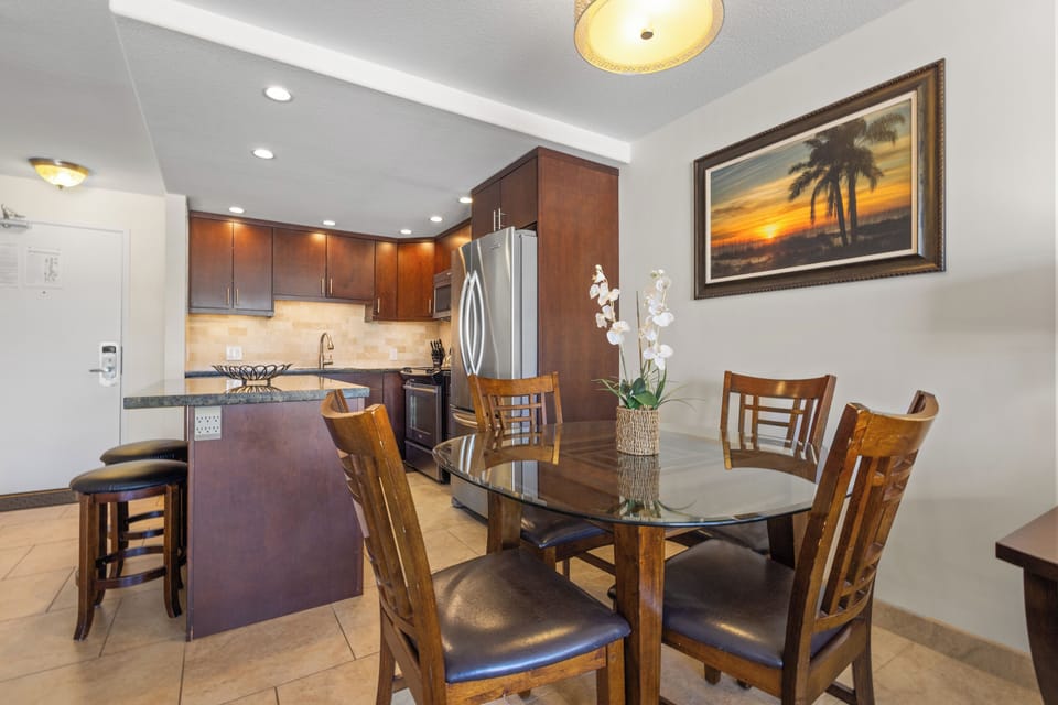 Gather around your elegant dining table while the open kitchen invites culinary adventures with sleek appliances and rich wood cabinetry.