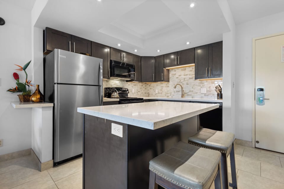 Your modern kitchen features sleek dark cabinets, stainless steel appliances, and a marble island perfect for cooking memorable meals.