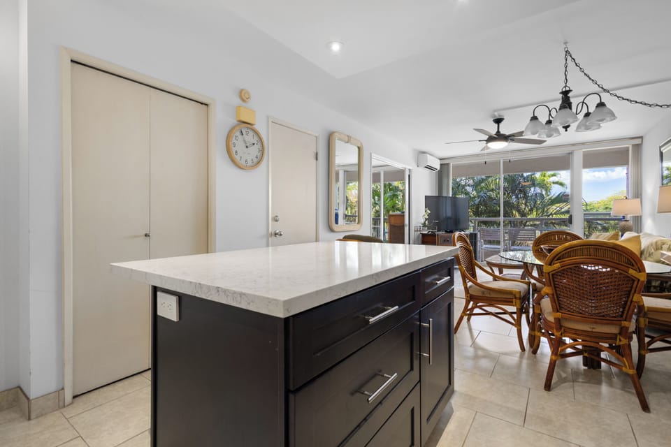 Your fully equipped kitchen flows seamlessly into the dining area, where tropical garden views create a peaceful backdrop for your morning coffee or evening meals.