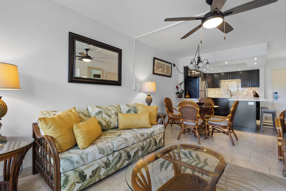 Relax in this bright, tropical-themed living space with comfortable seating, modern kitchen, and warm golden accents that create your perfect home away from home.
