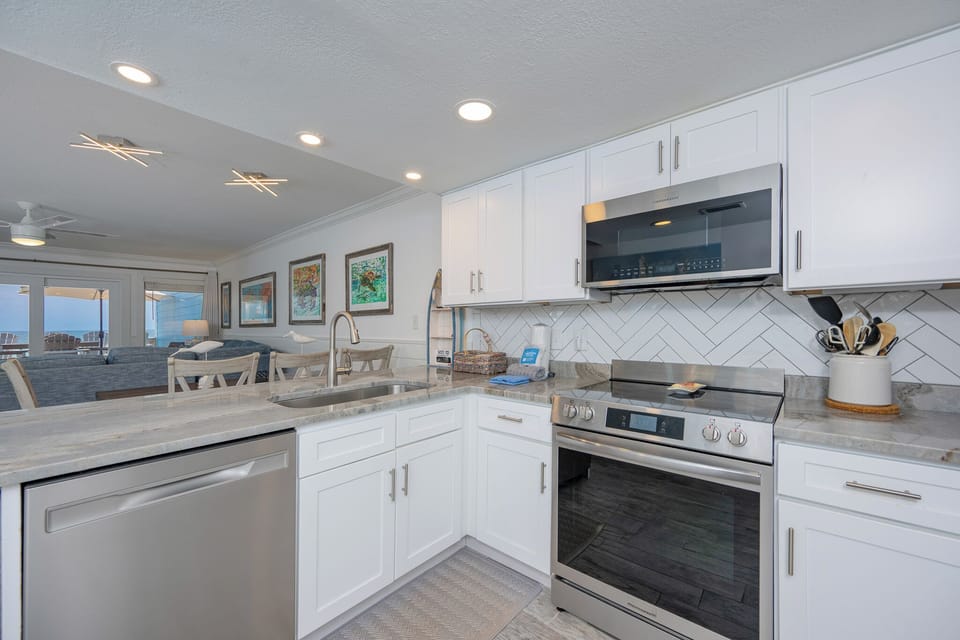 The kitchen's sleek counters and stainless steel set the scene for leisurely meal prep as you watch the coast