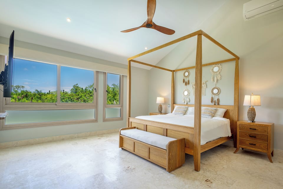 Spacious master bedroom with king bed, TV, and large windows