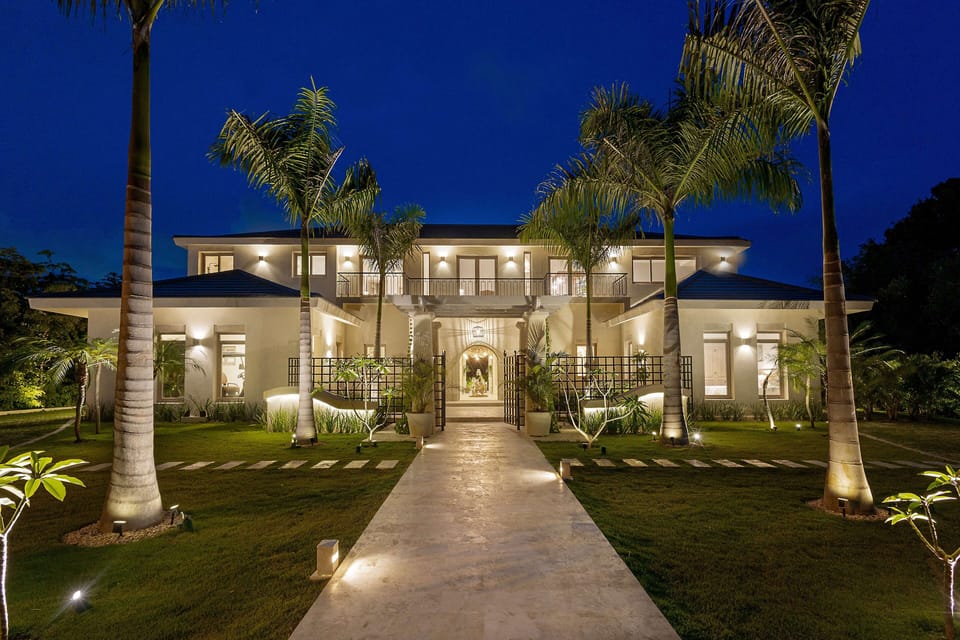 Stunning night view of the villa’s entrance with lit pathway and palms