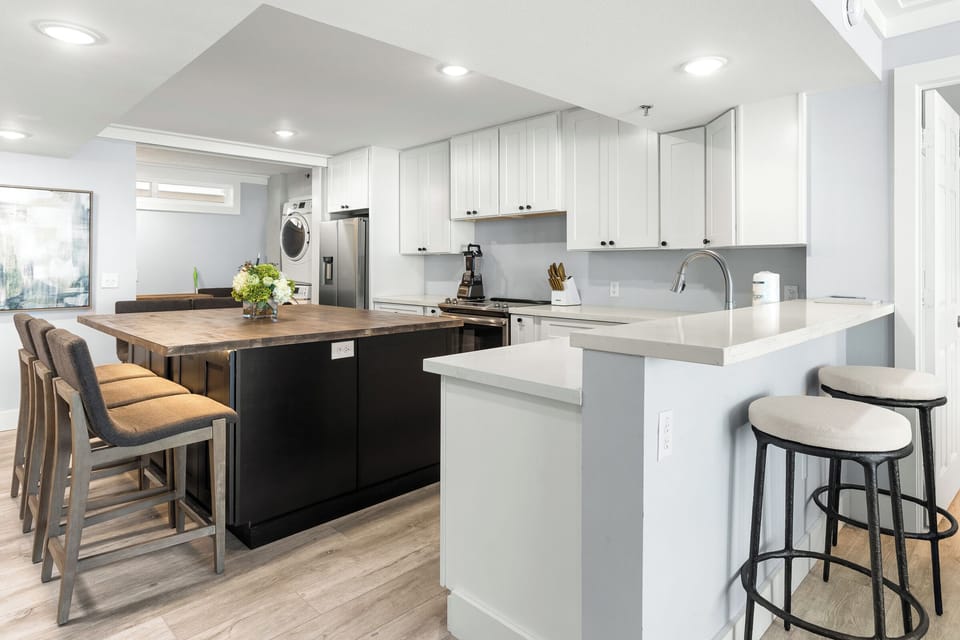 Your modern kitchen invites culinary adventures with sleek white cabinets, quartz countertops, and a spacious island perfect for morning coffee or evening gatherings.