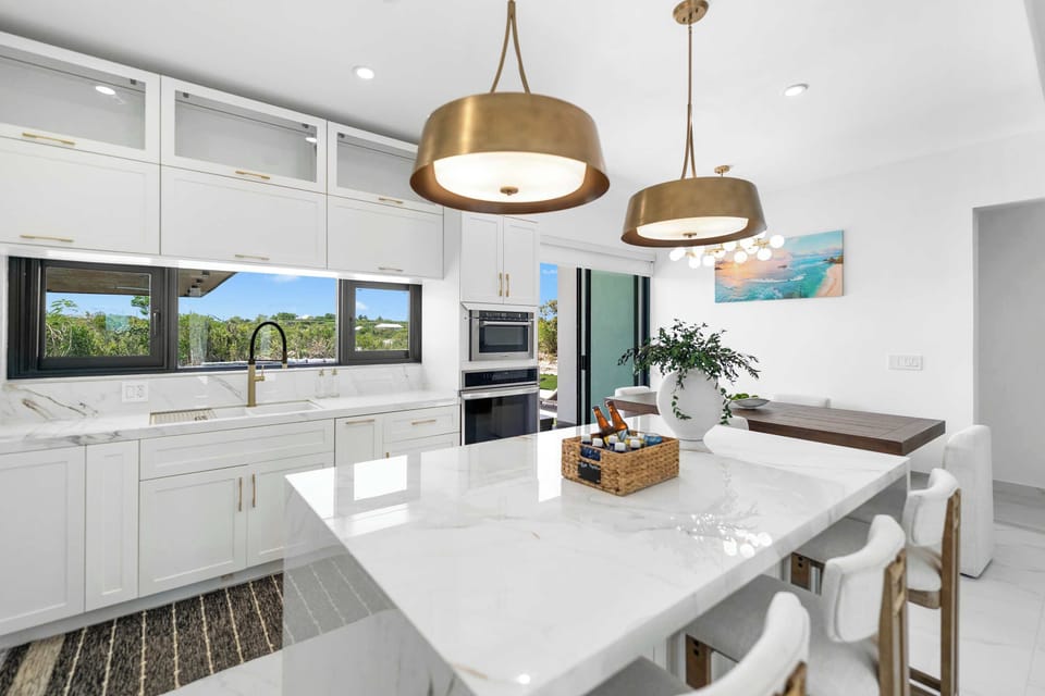 Chic gold pendant lights illuminate the marble kitchen island.