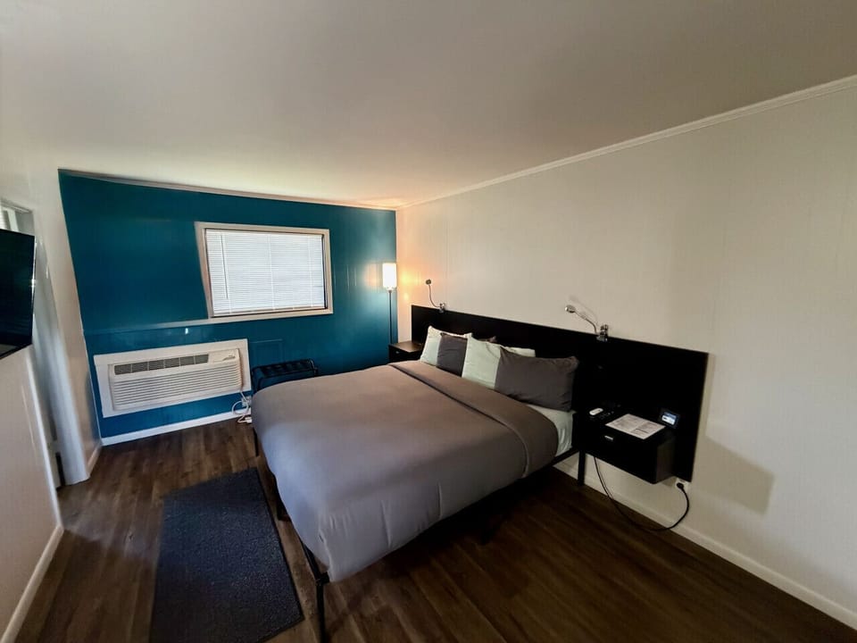 King bed with teal accent wall, reading lamps, and hardwood floors