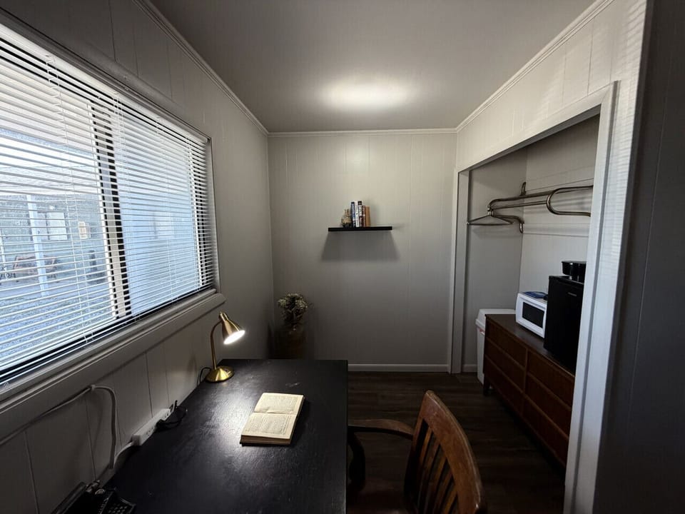 Writing nook with desk, open closet, coffee maker, and microwave
