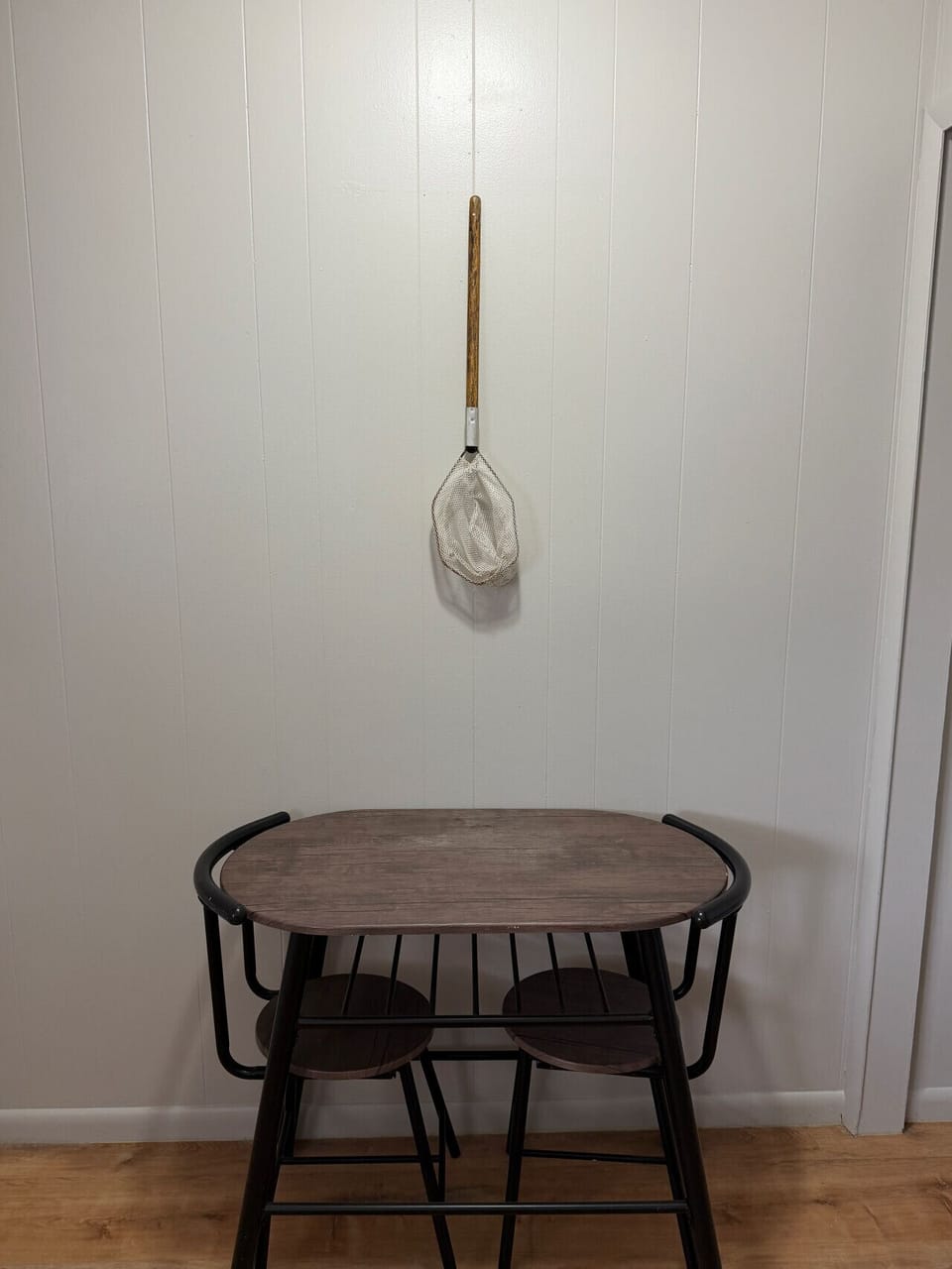 Vintage wooden-handled landing net hung above the in-room bistro table for coffee or a quick bite