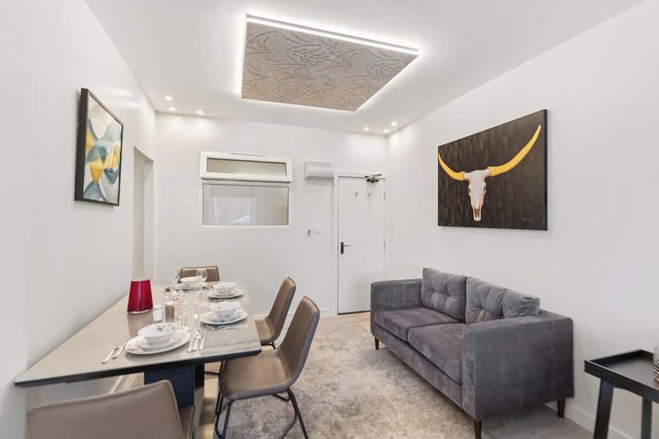 A modern dining space with a sleek table set for four, perfect for shared meals. Adjacent is a comfortable sofa for relaxing, complemented by contemporary artwork and soft lighting, creating a warm and inviting atmosphere.