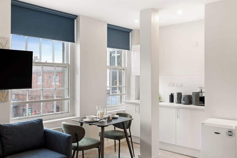 A bright, open-plan living space with large windows filling the room with natural light. Relax on the comfortable sofa with Smart TV, while the stylish dining area and modern kitchenette create a perfect space to unwind.