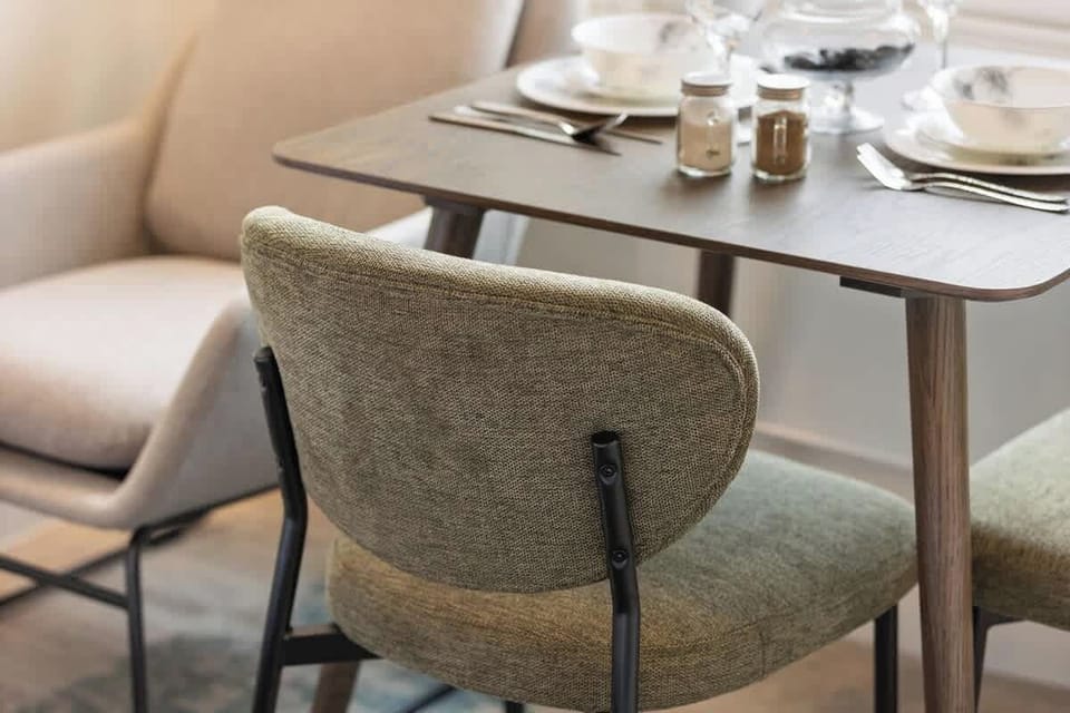 A beautifully styled dining area set within a bright, open-plan space. Featuring elegant décor, feature wall and modern furnishings, it offers a warm, sophisticated setting perfect for relaxed breakfasts, evening meals and social dining.