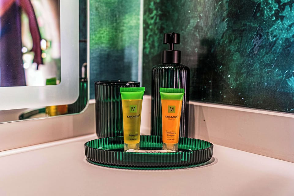 Green tea and mint spa toiletries arranged on a green tray in a modern bathroom.