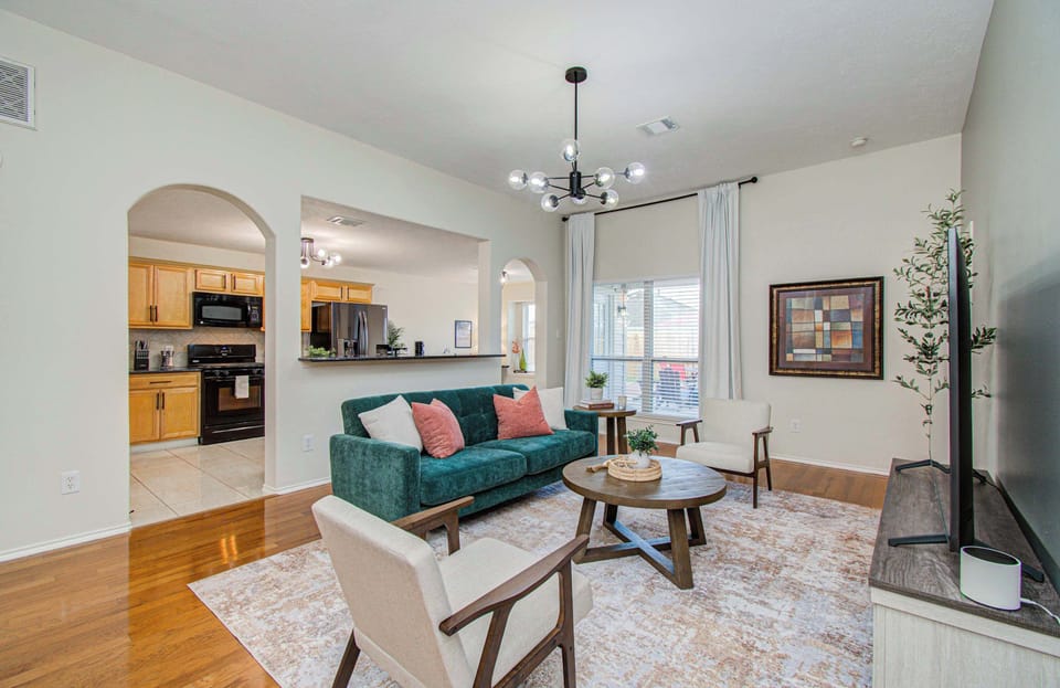 House 2: Bright, stylish living room with cozy seating, modern lighting, and an open flow into the kitchen—perfect for relaxing or gathering in comfort.