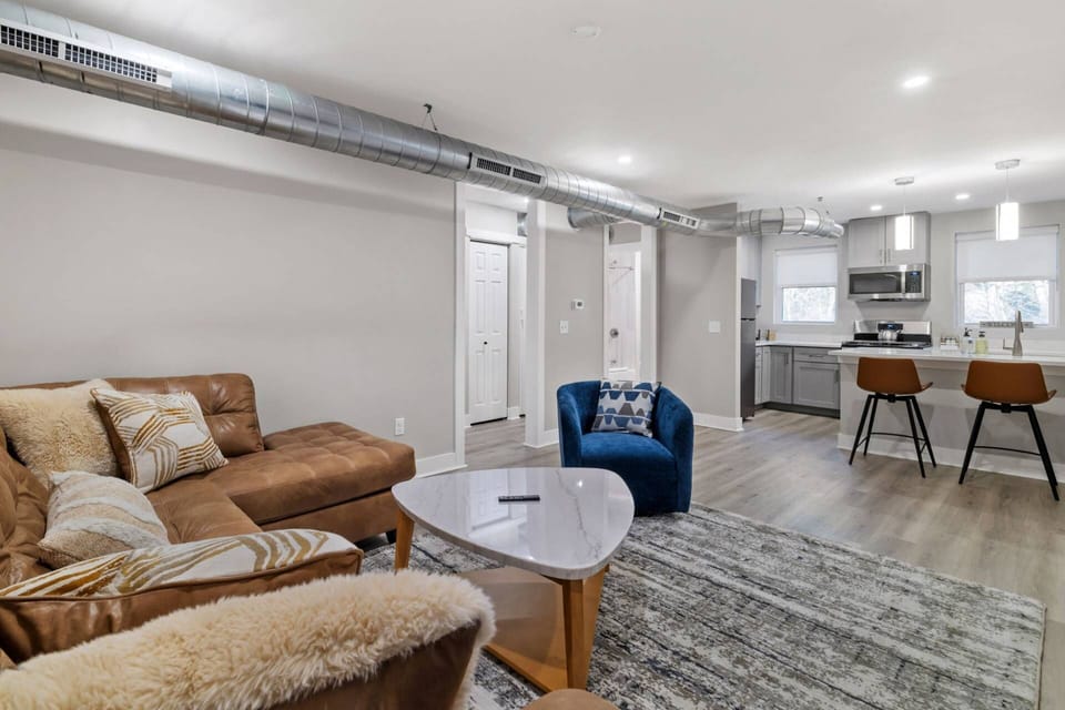 Wide-angle view of the full open-concept living and kitchen space with loft-style exposed ductwork throughout.