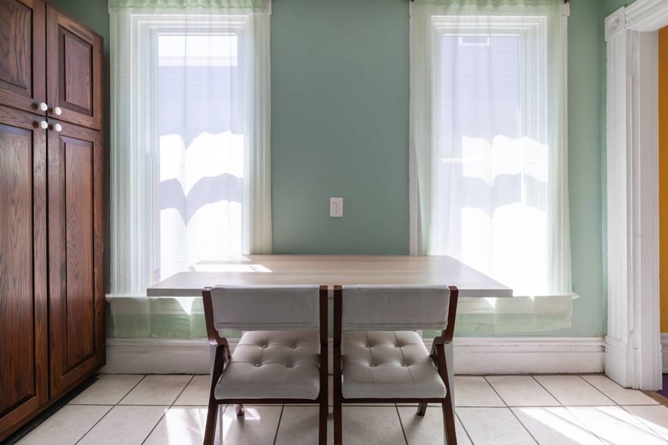 Bright dining table for two by the kitchen windows, a quiet spot for meals or morning coffee.
