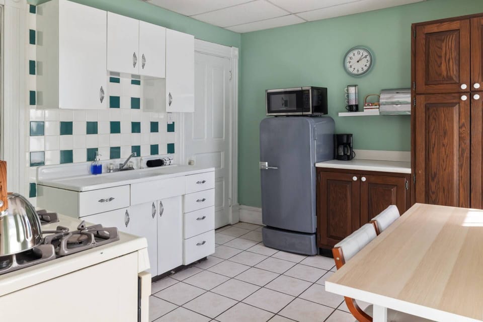 Full kitchen with vintage-style refrigerator, original metal cabinets, checkerboard tile, and dining table for two.