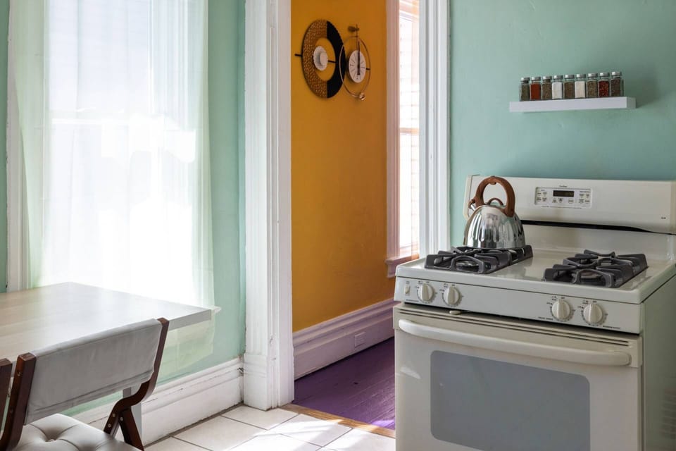 Dining table for two by the kitchen window, with the gas stove and spice rack close at hand.