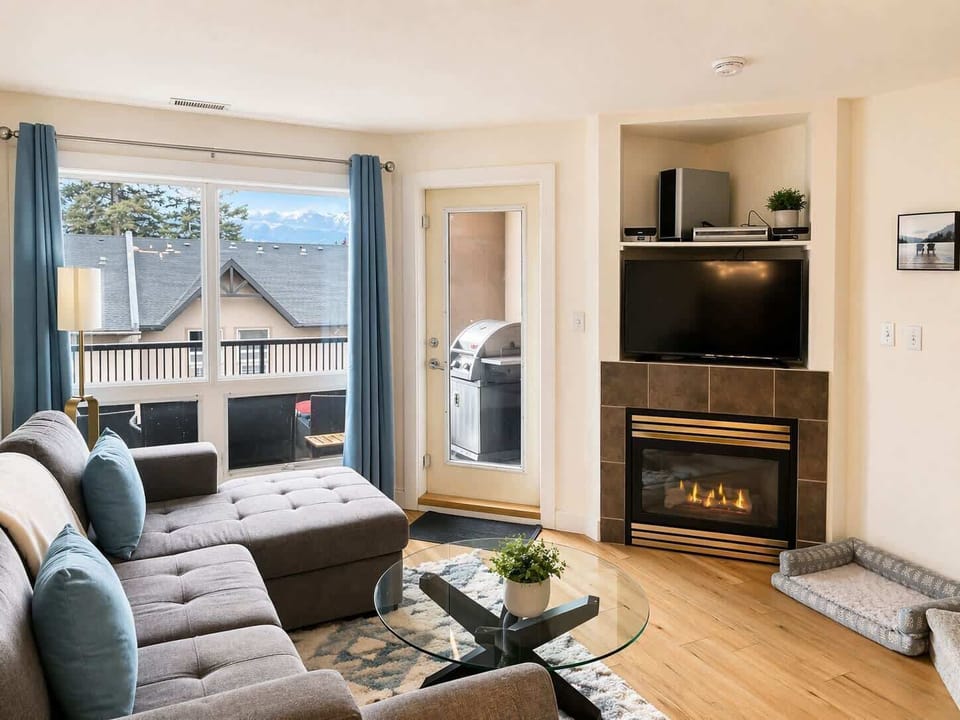 Comfy living room with gas fireplace, TV and relaxed seating for humans and 4 legged friends alike. The living room leads out onto the deck which has a BBQ and seating to soak up the views.