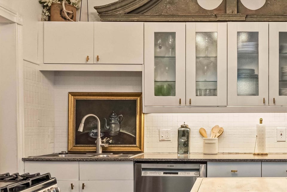Kitchen detail featuring modern cabinetry, farmhouse-style sink, and stainless steel dishwasher.