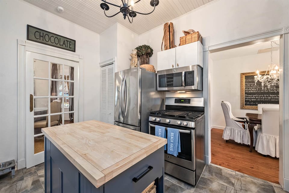 Fully equipped kitchen with stainless steel refrigerator, gas stove, microwave, and center island with prep space.