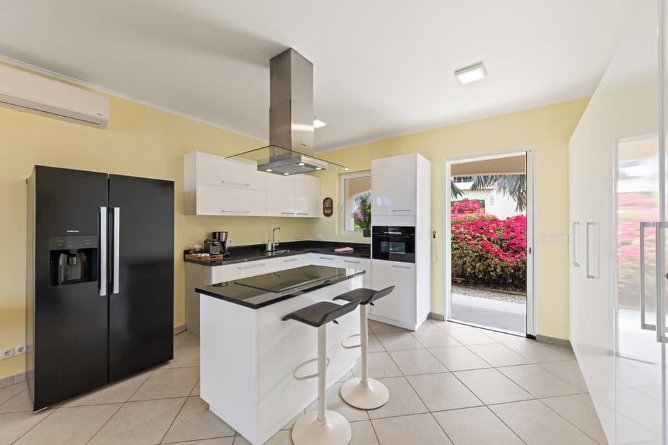 Fully equipped kitchen with modern appliances, island seating and direct access to outdoor space