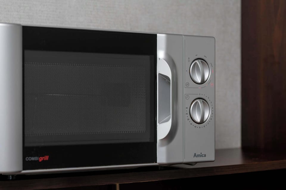 A close-up of a microwave placed in the kitchenette area. The appliance is modern and easy to access.