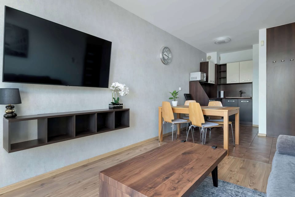 A stylish living room corner with a mounted TV and minimalist furniture. The decor is simple and contemporary.