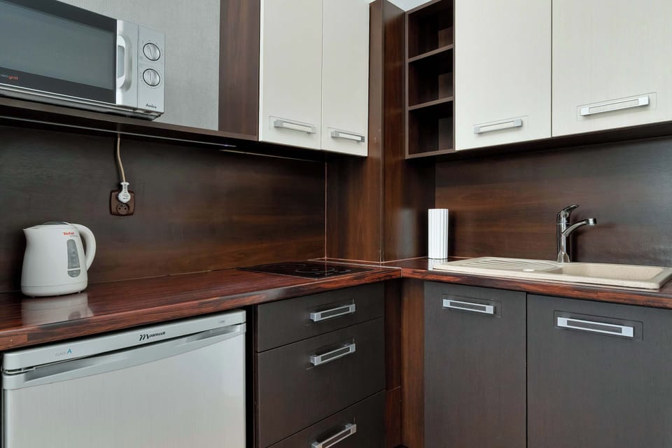 A fully equipped kitchenette  with dark cabinets and modern appliances. The countertop provides enough space for cooking and meal prep.