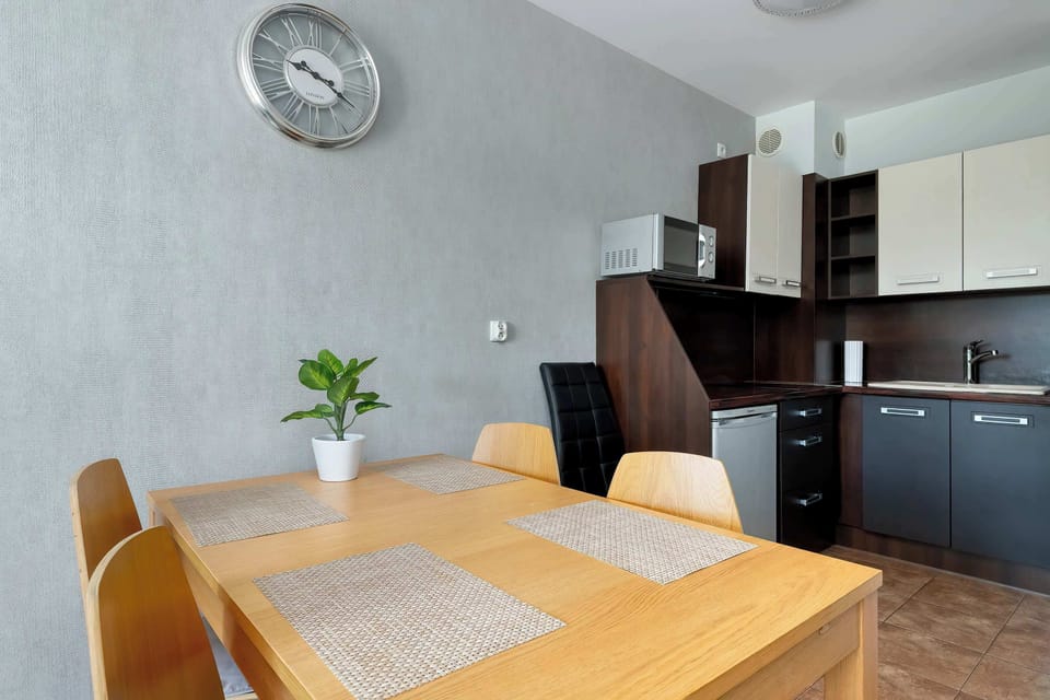 A dining area with a wooden table and chairs placed next to a compact kitchen. The space is neat and well-organized.