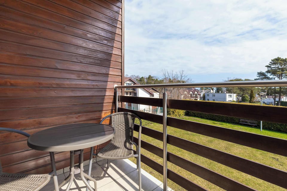 A balcony with wooden railing panels and a view of nearby buildings and greenery. The space is ideal for enjoying fresh air and outdoor relaxation.