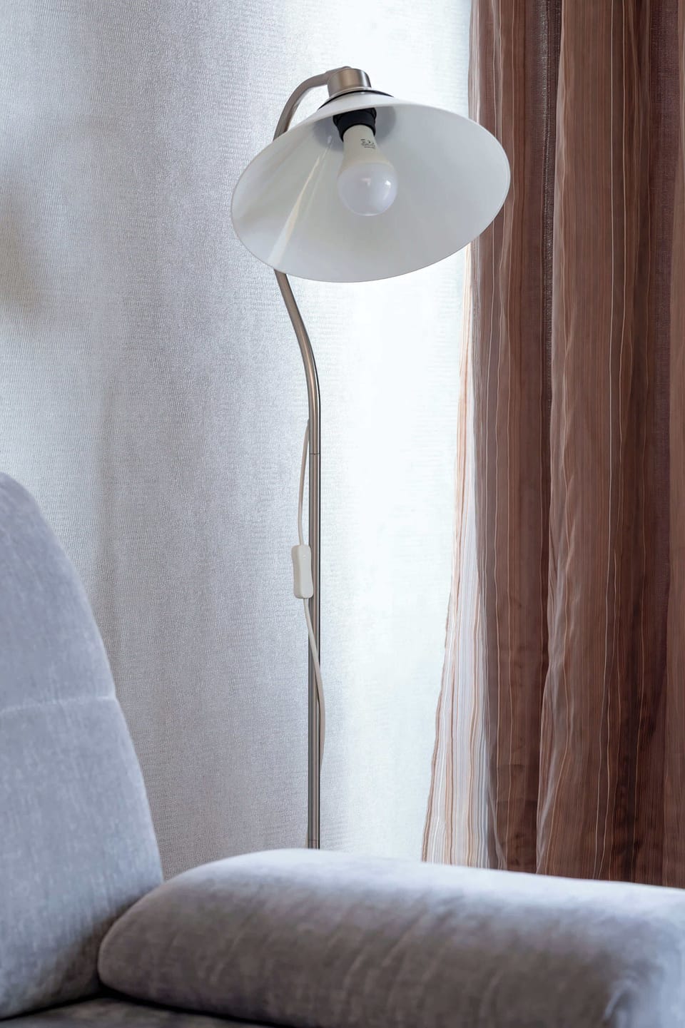 A close-up of a floor lamp next to a seating area. The lighting fixture adds warmth and ambiance.