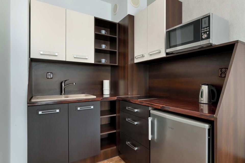 A compact kitchenette with dark cabinets, built-in appliances, and a modern finish. The layout is efficient, making good use of limited space.