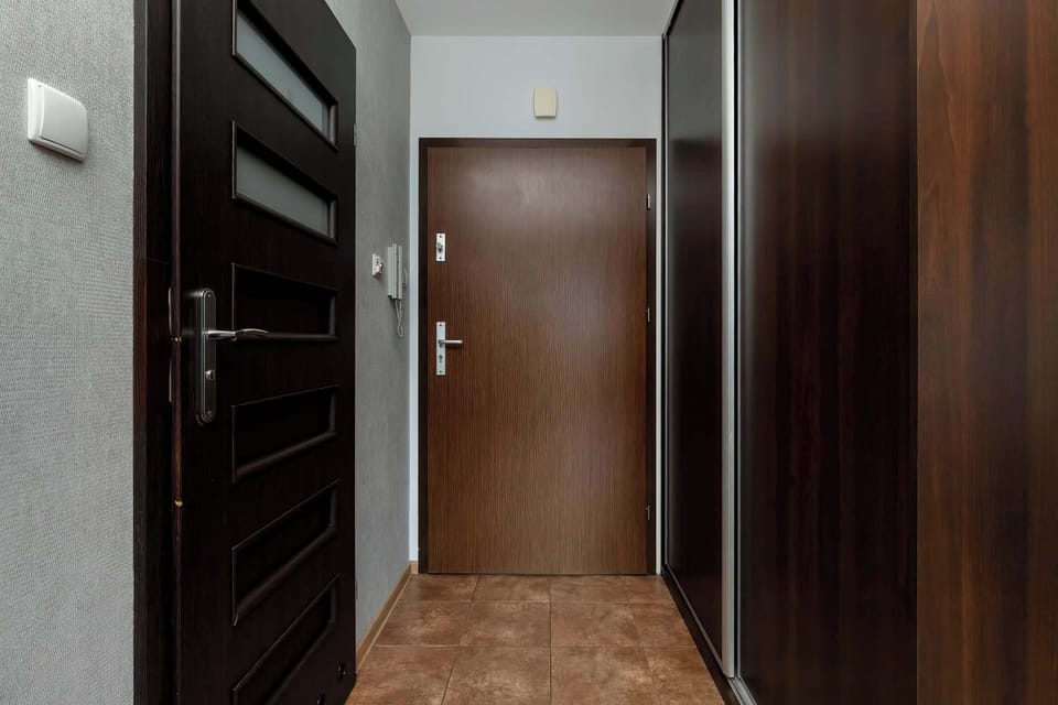 An entryway with a wardrobe and a dark front door. The space is practical for storage and welcoming guests.