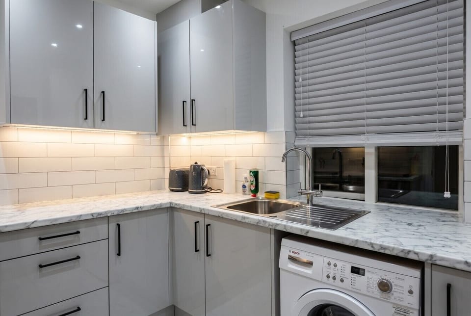 Full kitchen overview showing ample worktop space, gloss cabinets and a Bosch washing machine built in.